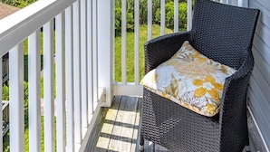 A covered porch with a wicker chair and a view of a coastal landscape. - Sunset Overlook, Spacious bay side top-floor condo with amazing views  (Ocean City)