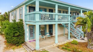 A two-story building with a balcony, a staircase, and a door marked with a 'C'. - Condo steps to beach w/ daily attraction perks (Panama City Beach)