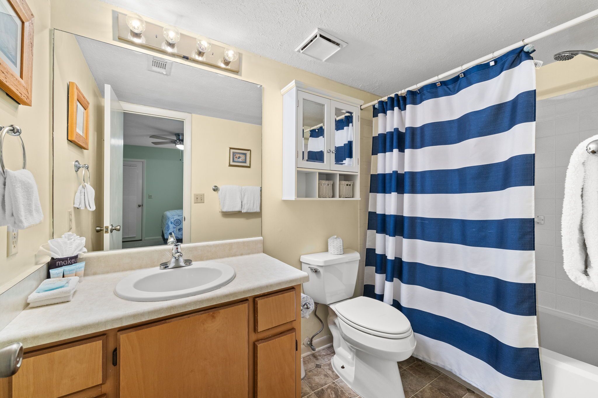 Une salle de bain équipée d’un lavabo, d’un miroir, d’un meuble de rangement, de toilettes et d’un rideau de douche.