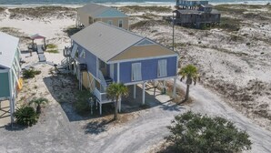 A beachfront property with multiple buildings, including a large house with a covered porch and a smaller structure. - La De Da | 3BR/2BA Fort Morgan Home | Sleeps 8 | Gulf Views & Bunkroom Fun (Gulf Shores)