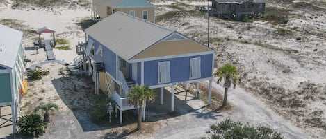 Una propiedad frente a la playa con varias construcciones, incluyendo una casa grande con porche cubierto y una estructura más pequeña.