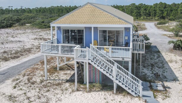A beach house with a balcony, a staircase, and a view of the beach. - La De Da | 3BR/2BA Fort Morgan Home | Sleeps 8 | Gulf Views & Bunkroom Fun (Gulf Shores)