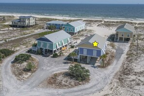 A coastal property with multiple beachfront houses, a dirt road, and a clear view of the ocean. - 3BR/2BA Fort Morgan Home | Sleeps 8 | Gulf Views & Bunkroom Fun (Gulf Shores)