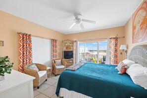 A bedroom with a bed, a chair, a TV, and a balcony with a view. - 3BR/2BA Fort Morgan Home | Sleeps 8 | Gulf Views & Bunkroom Fun (Gulf Shores)