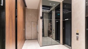A modern elevator area with a mirrored wall, a wooden panel wall, and a tiled floor. - Luxury 3 BDR  In The Heart Of Jerusalem By Isrentals (Jerusalem)