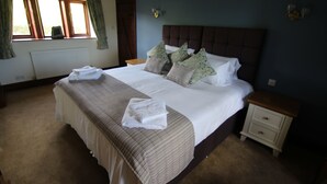 A neatly made bed with a brown headboard, a bedside table, and a window with curtains. - Idyllic cottage in Slaithwaite, stunning views, heart of the countryside (Upper Holme)