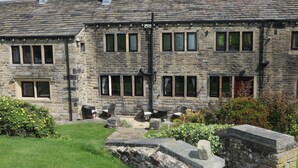 A stone building with multiple windows and a stone pathway leading to a seating area. - Idyllic cottage in Slaithwaite, stunning views, heart of the countryside (Upper Holme)