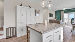 A modern kitchen with white cabinetry, a granite countertop, and pendant lighting. - Coastal Retreat: Elevator, Pool now open, Walk to Beach! (North Topsail Beach)