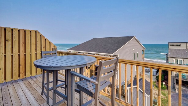 A wooden deck with a table and chairs overlooking the ocean. - Coastal Retreat: Elevator, Pool now open, Walk to Beach! (North Topsail Beach)