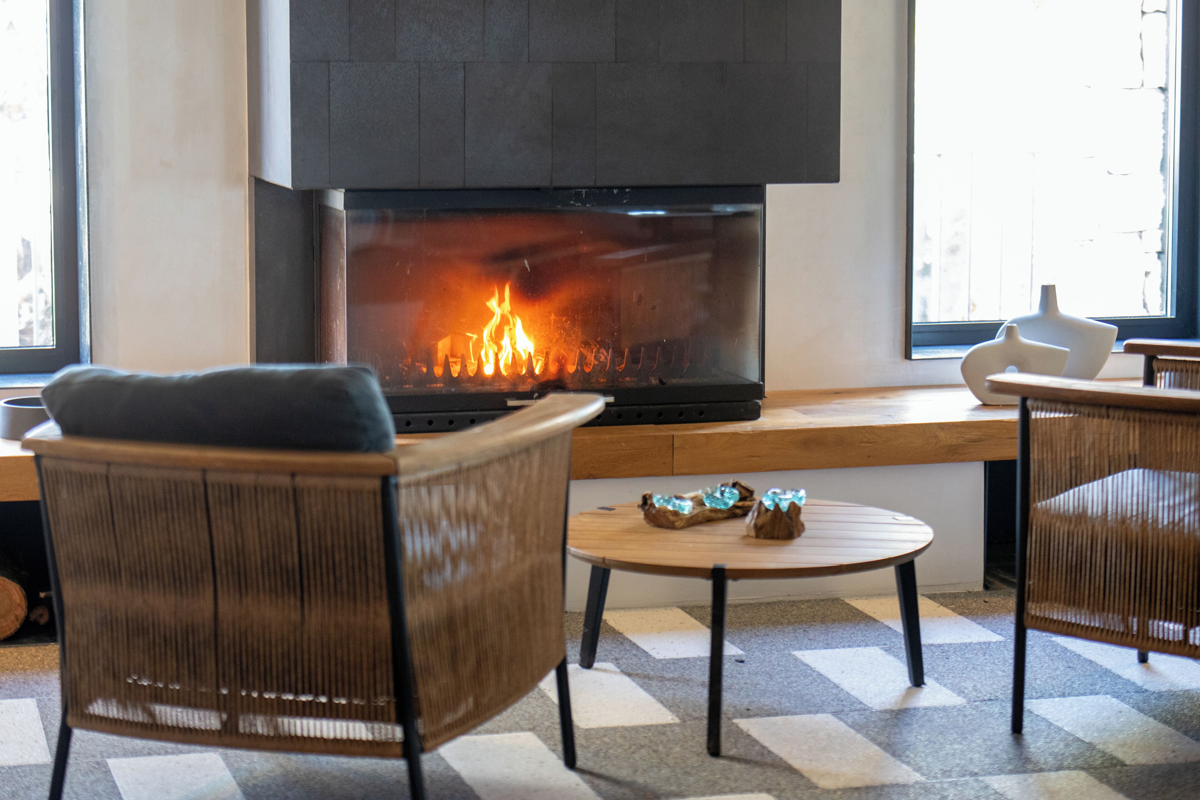 Un interior moderno con chimenea, mobiliario de mimbre y piso a cuadros.