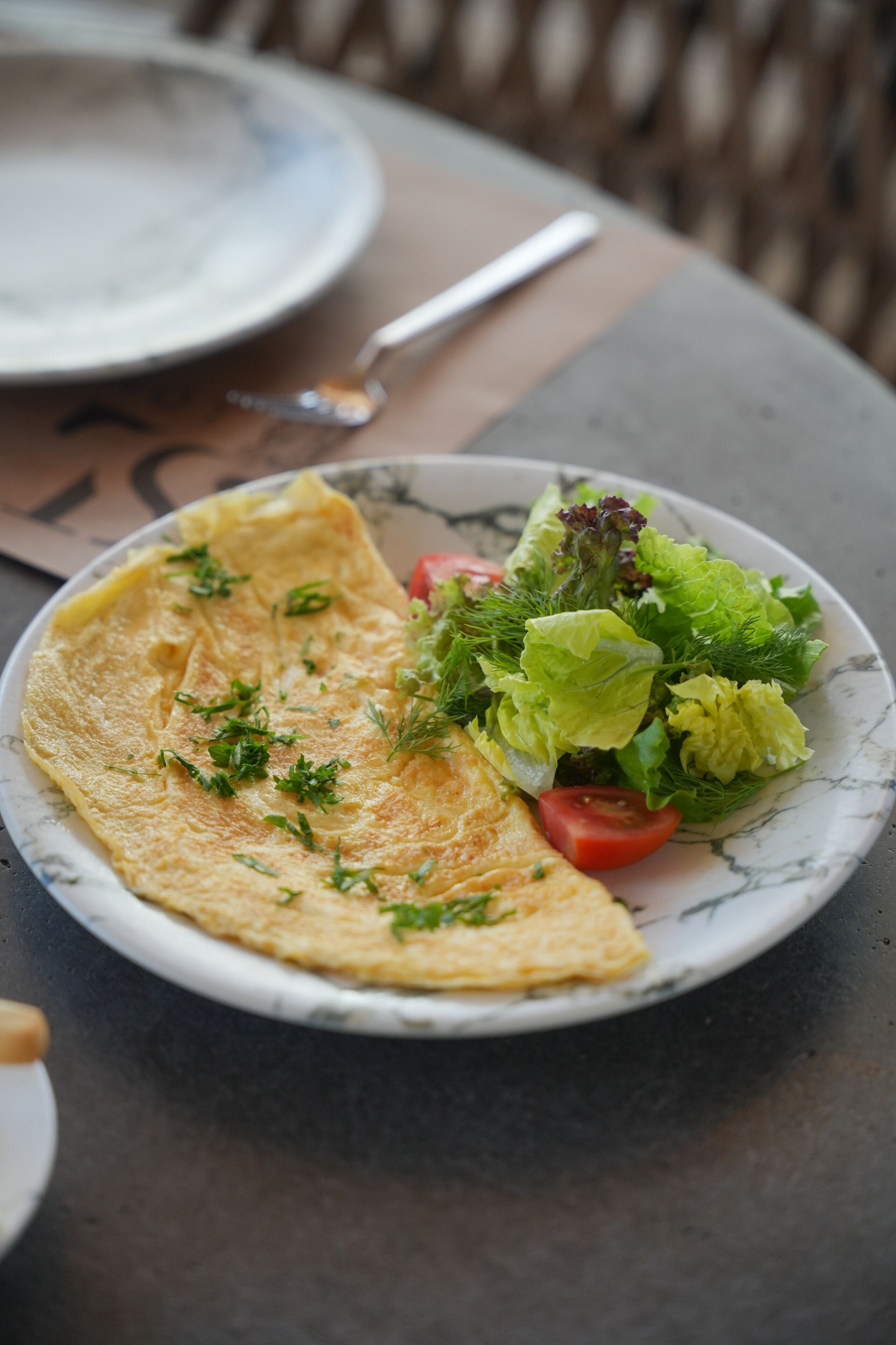 Un plato con tortilla y una ensalada al lado, sobre una mesa.