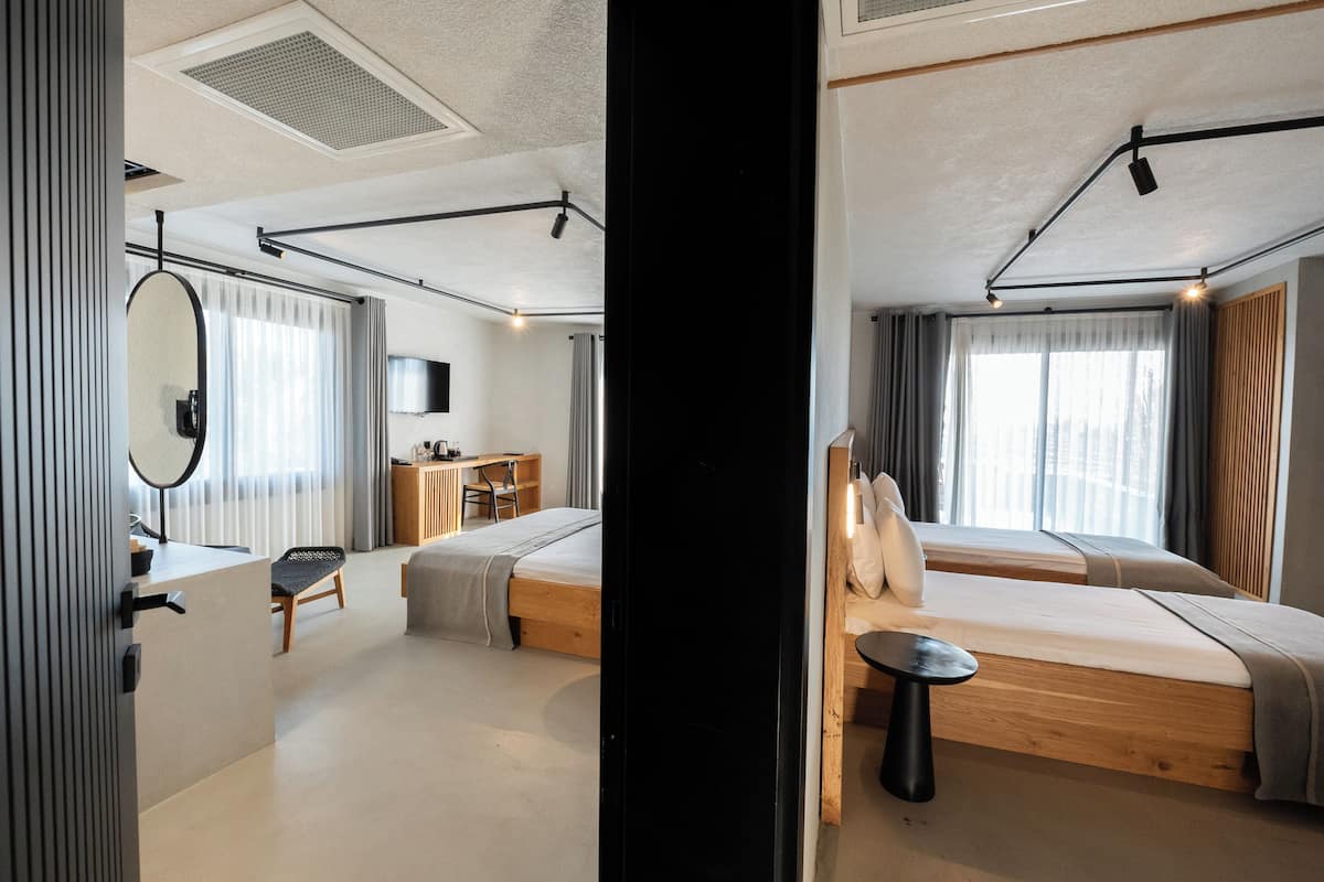 A modern hotel room with a bed, desk, chair, and a small table.