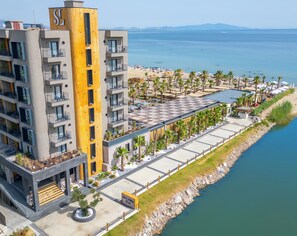 A modern hotel with a central courtyard, a pool area, and a beach view. - Ayvalık Sea Long (Ayvalik)