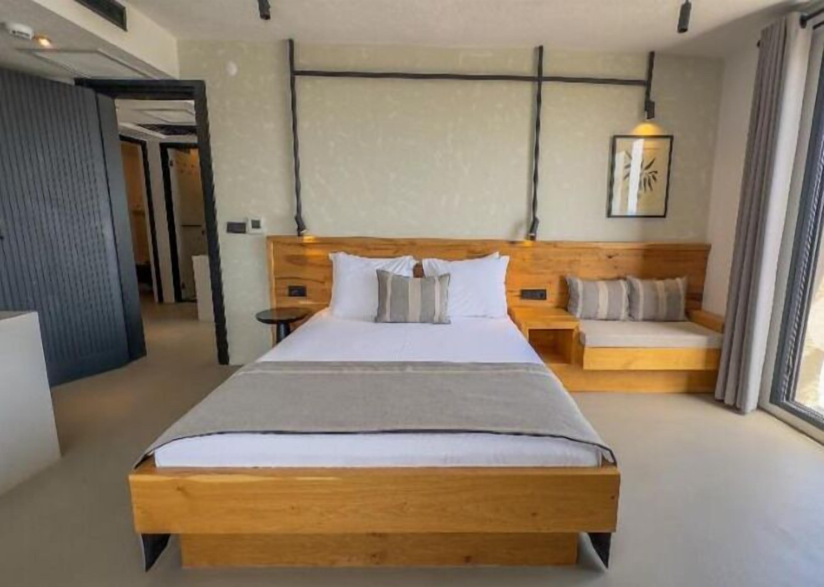 Un dormitorio con una cama de madera, mesitas de noche, un sofá y una lámpara fijada a la pared.