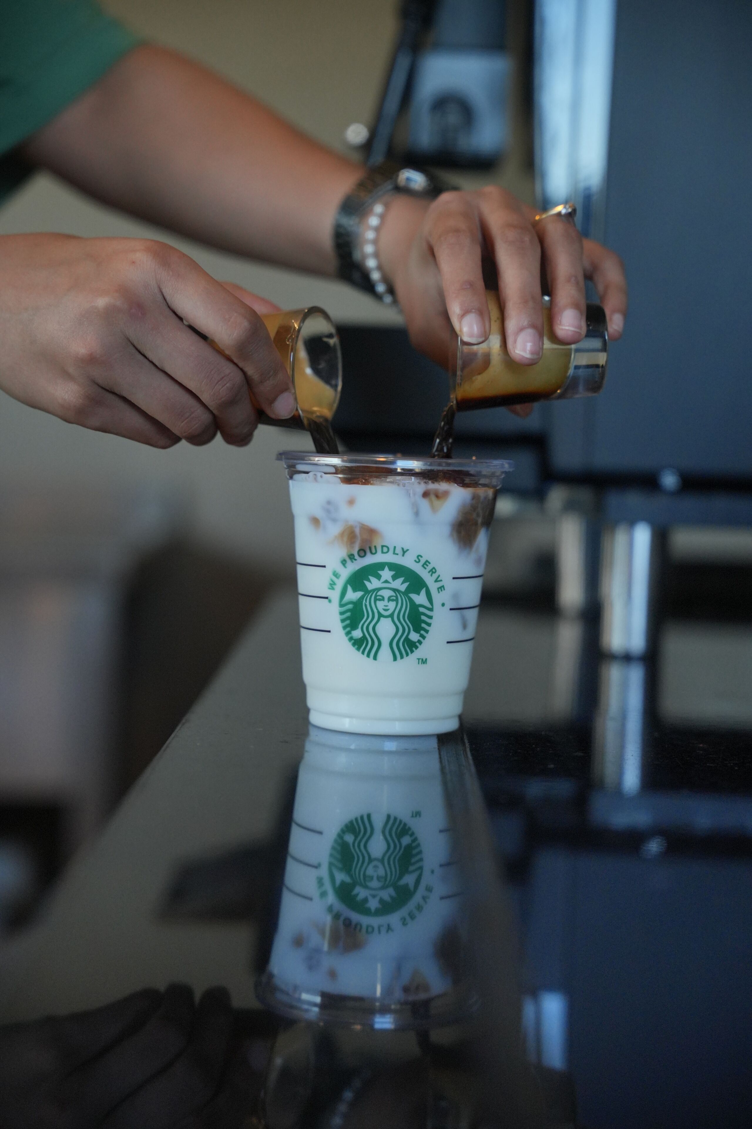 A person pouring a beverage into a Starbucks cup.