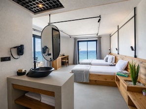 A modern hotel room with a large bed, a desk, a mirror, and a view of the sea. - Ayvalık Sea Long (Ayvalik)