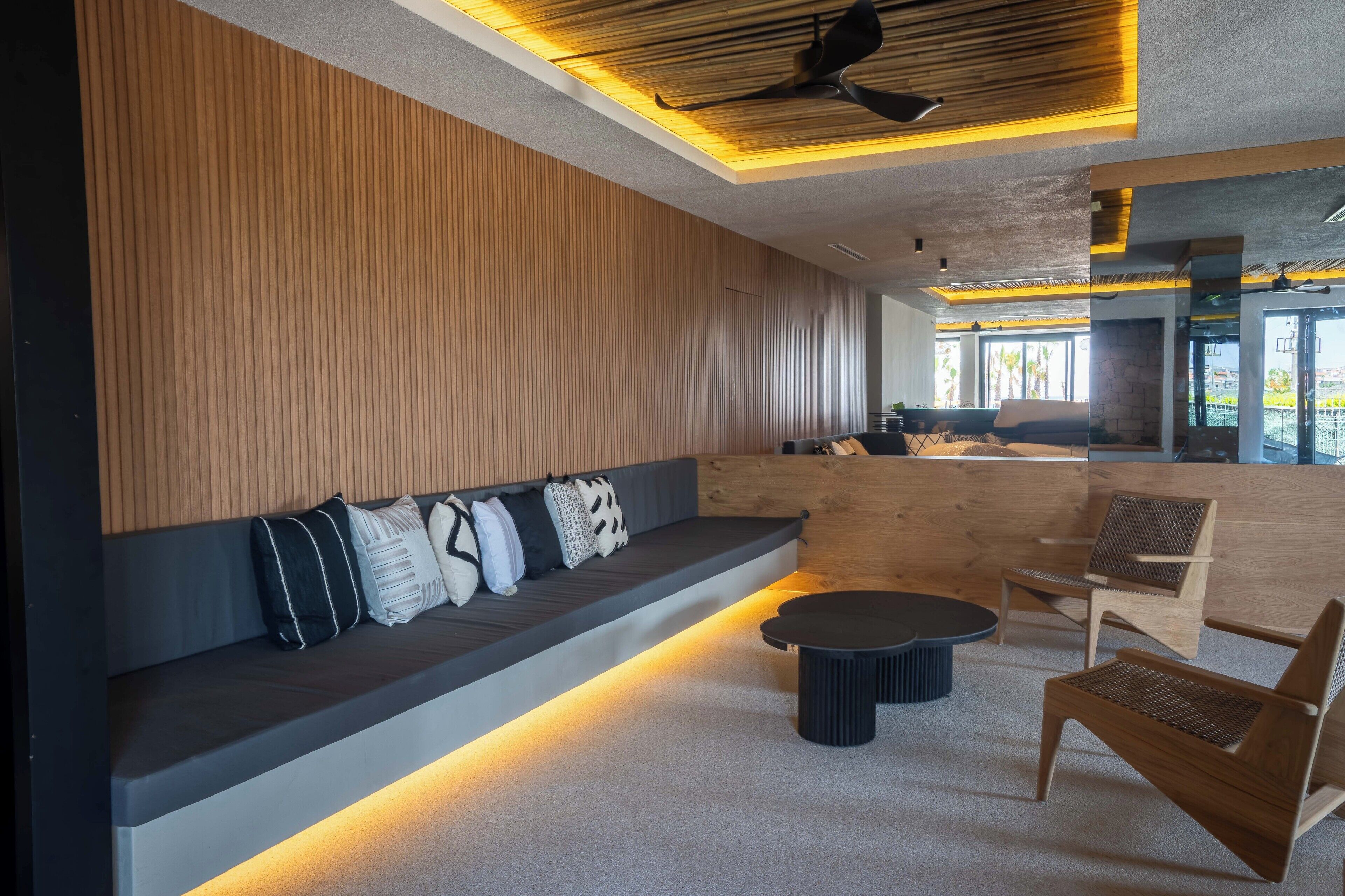 Ein moderner Lounge-Bereich mit einer Holzwand, einer Sitzbank mit Kissen und einem runden Tisch.