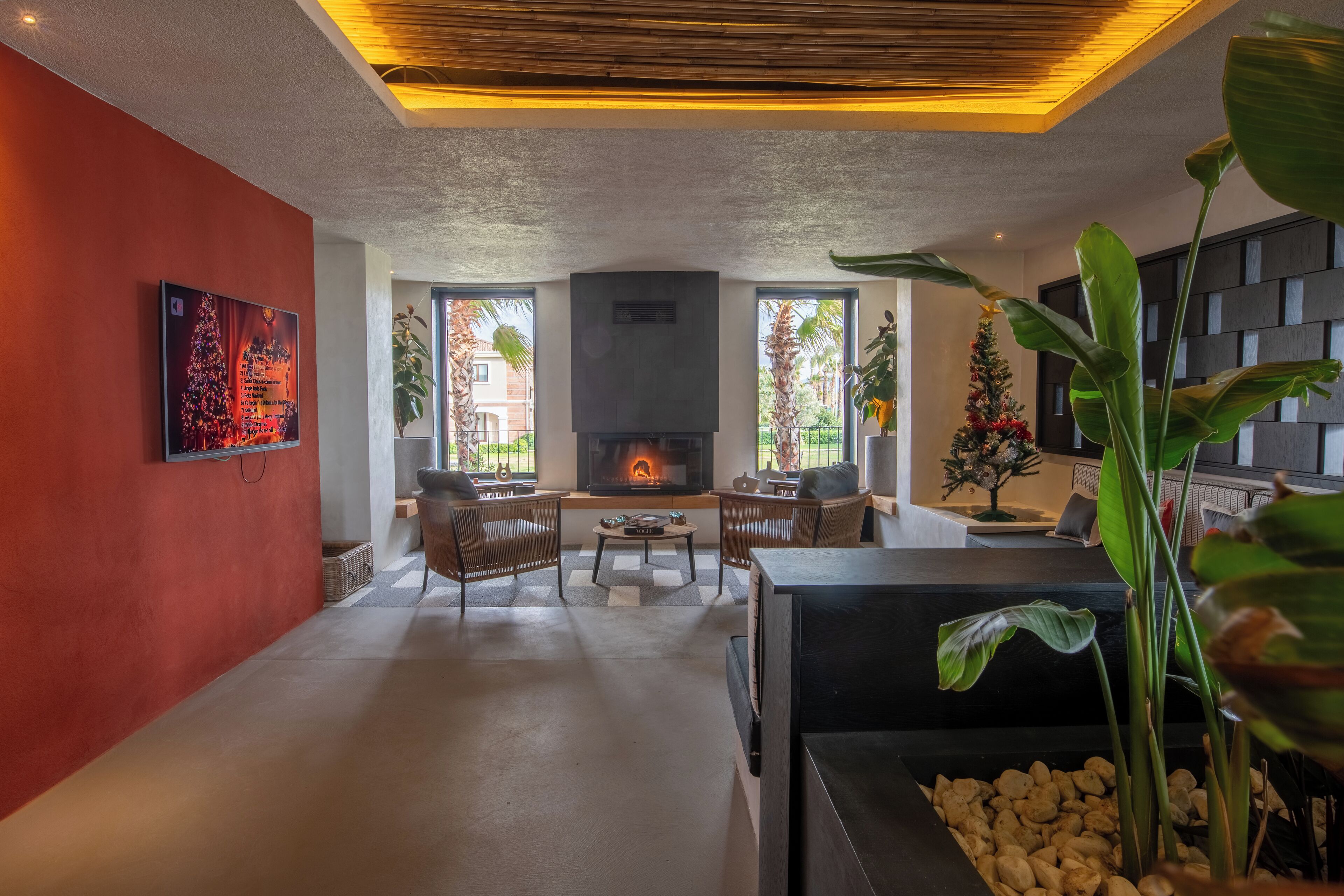 A modern living room with a fireplace, comfortable seating, and large windows.