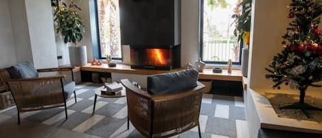 A modern living room with a fireplace, two wicker chairs, a coffee table, and a Christmas tree.