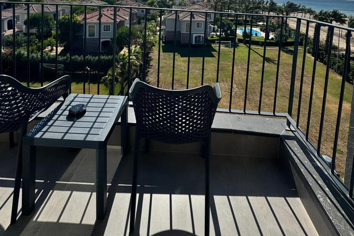 A balcony with a view of a residential area, a pool, and a clear sky.