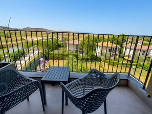 A balcony with a table and two chairs, overlooking a residential area with houses and greenery. - Ayvalık Sea Long (Ayvalik)