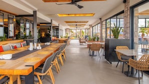 A spacious indoor dining area with long wooden tables, wicker chairs, and a ceiling fan. - Ayvalık Sea Long (Ayvalik)