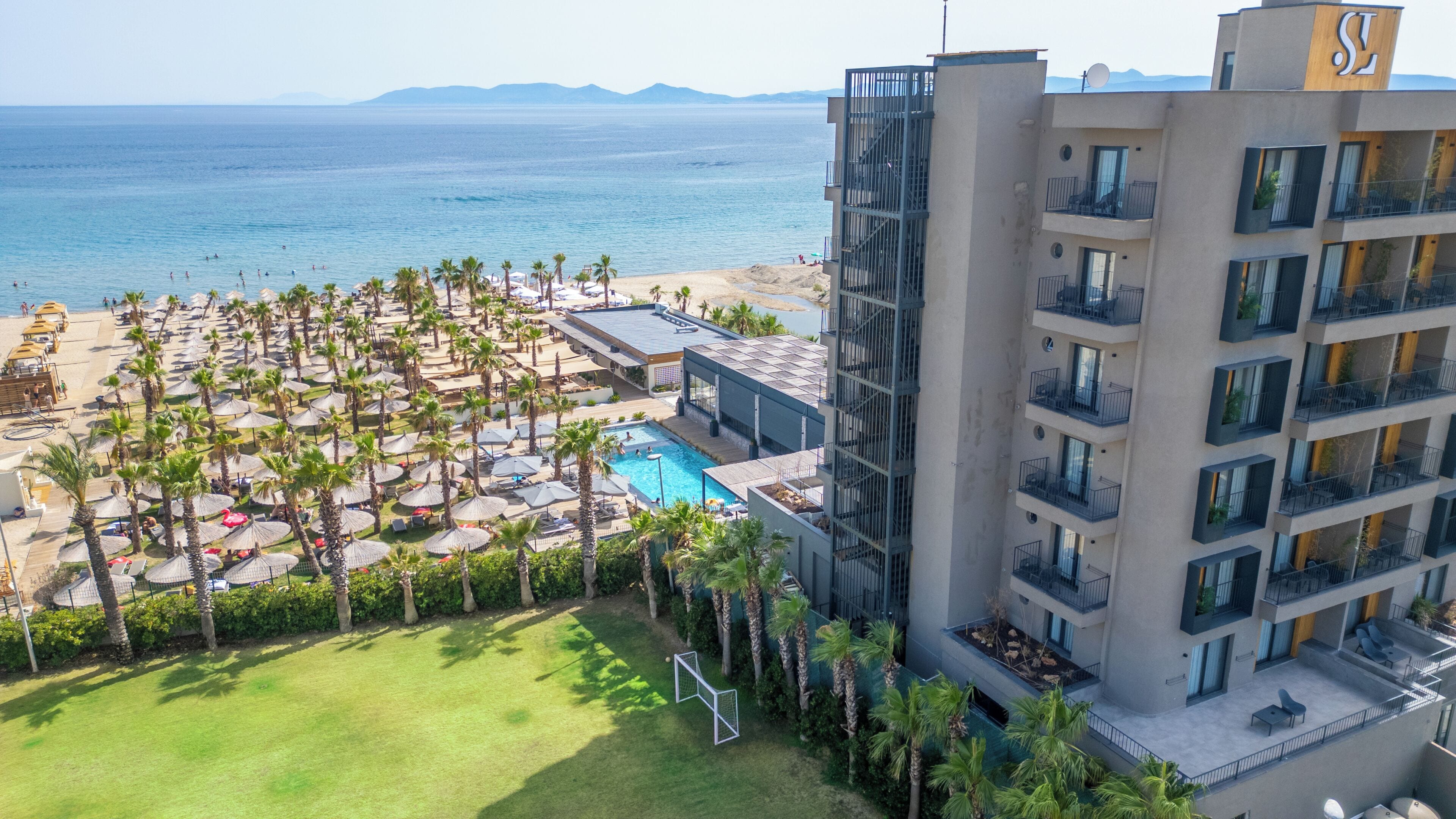 A hotel with a pool, beach, and palm trees.