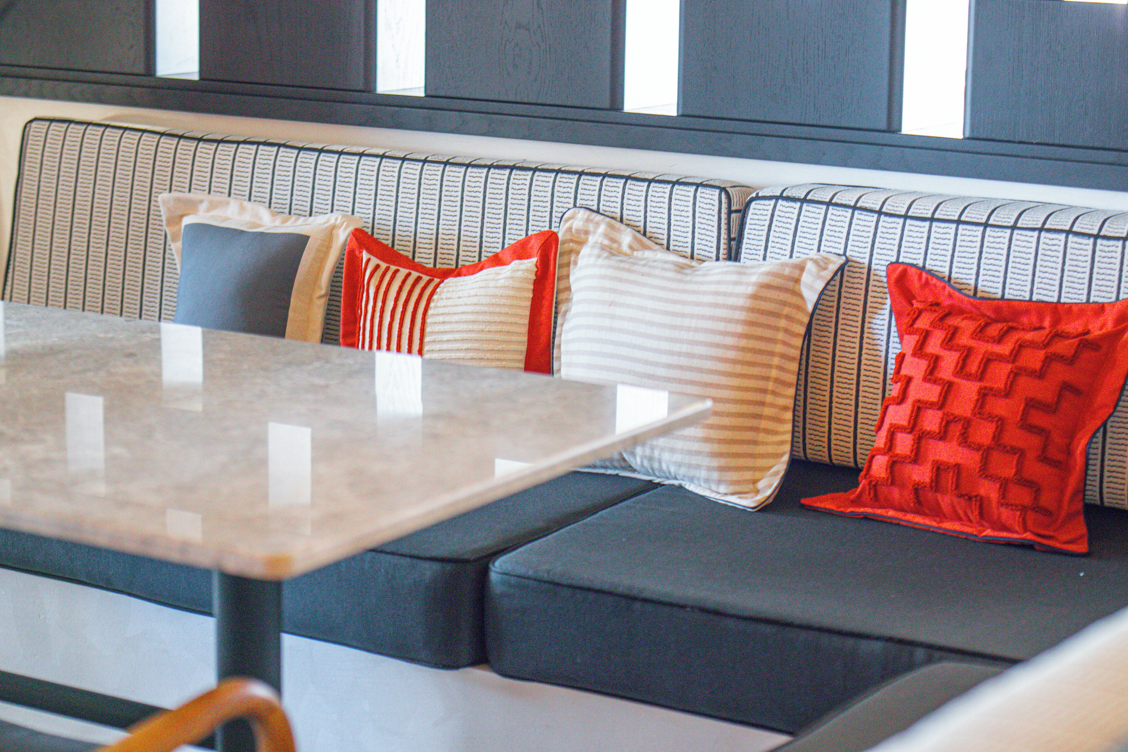 A seating area with a table, cushioned benches, and patterned cushions.