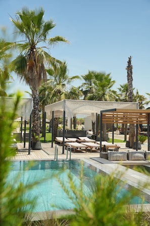 A pool area with lounge chairs, palm trees, and a pergola. - Ayvalık Sea Long (Ayvalik)