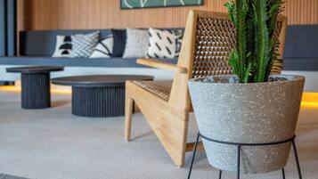 Una sala de estar moderna con techo de madera, ventilador de techo, sofá con cojines estampados, una mesa de centro y una planta en maceta.