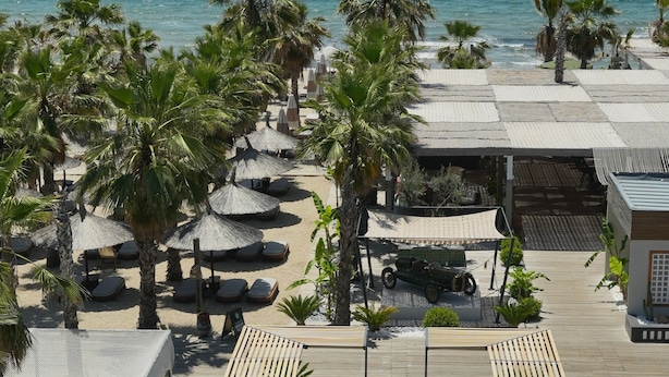 A pool area with lounge chairs and umbrellas, a wooden deck, and a view of the ocean. - Ayvalık Sea Long (Ayvalik)