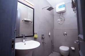 A modern bathroom with a sink, mirror, shower, and toilet. - F9 Hotels (New Delhi)