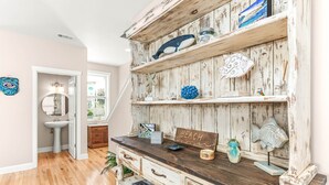 A rustic wooden shelf with decorative items, a wooden bench, and a sign that reads "BEACH". - Peach Coral | Mid Island, Game Room, Walk to Beach (Tybee Island)
