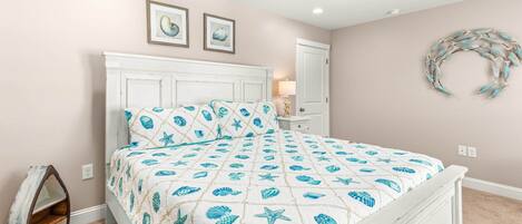 A bedroom with a bed, a ceiling fan, and a wall decoration.