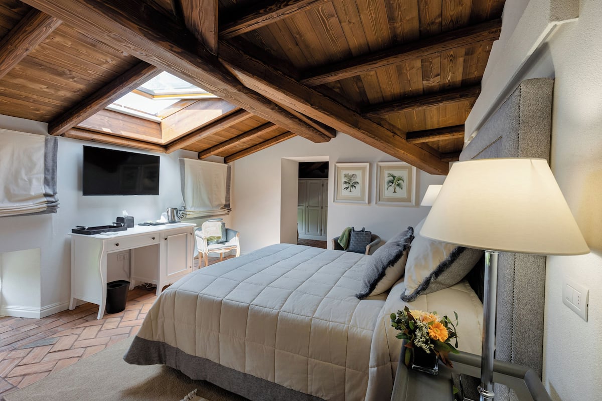 A bedroom with a bed, desk, and skylight.