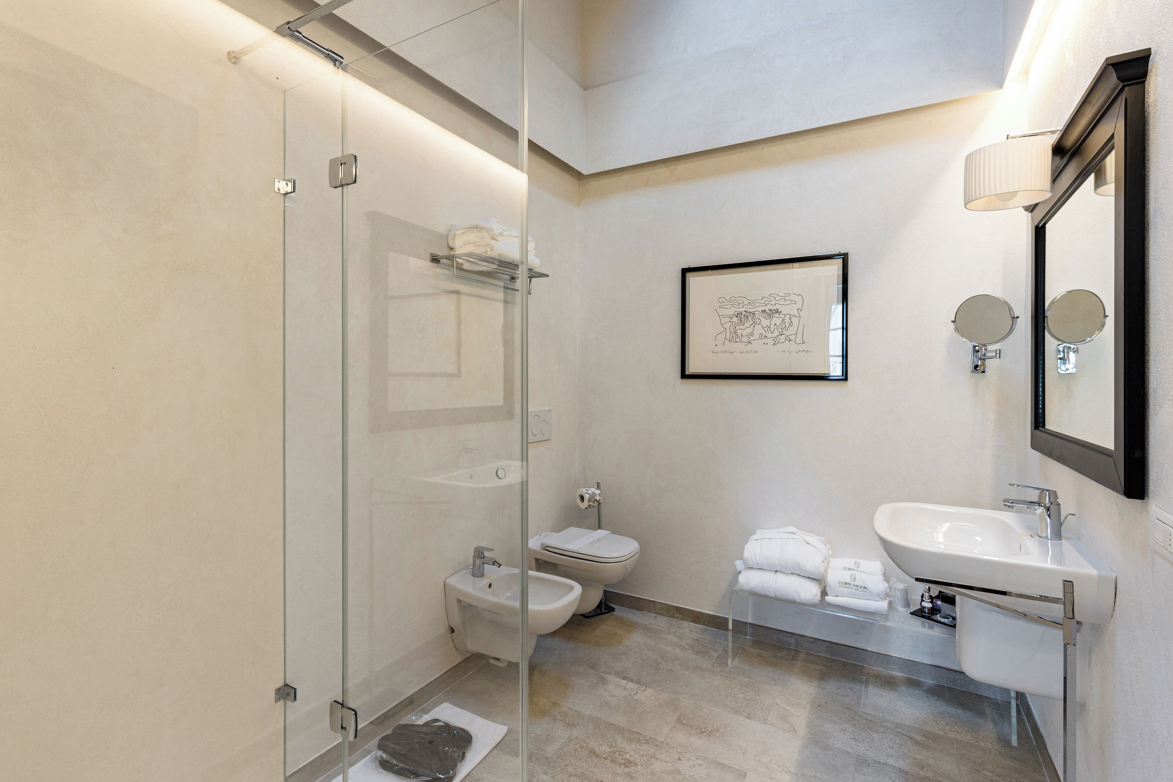 A modern bathroom with a glass shower enclosure, a bidet, a toilet, and a sink with a mirror.