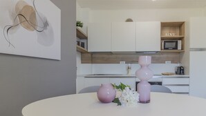 Une cuisine moderne avec des armoires blanches, un four à micro-ondes et une étagère en bois ornée d'un panneau indiquant le mot « AMOUR ».