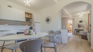 Une cuisine moderne avec des meubles blancs, un four à micro-ondes et un vase rose posé sur le plan de travail.