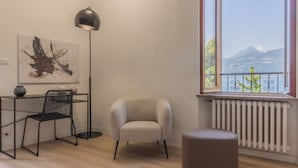 Une pièce avec vue sur la montagne, un radiateur, une chaise, un bureau et une lampe sur pied.