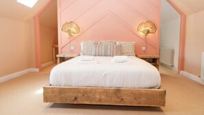 A bedroom with a large bed, two bedside lamps, and a wooden headboard. - The Workshop (Northallerton)