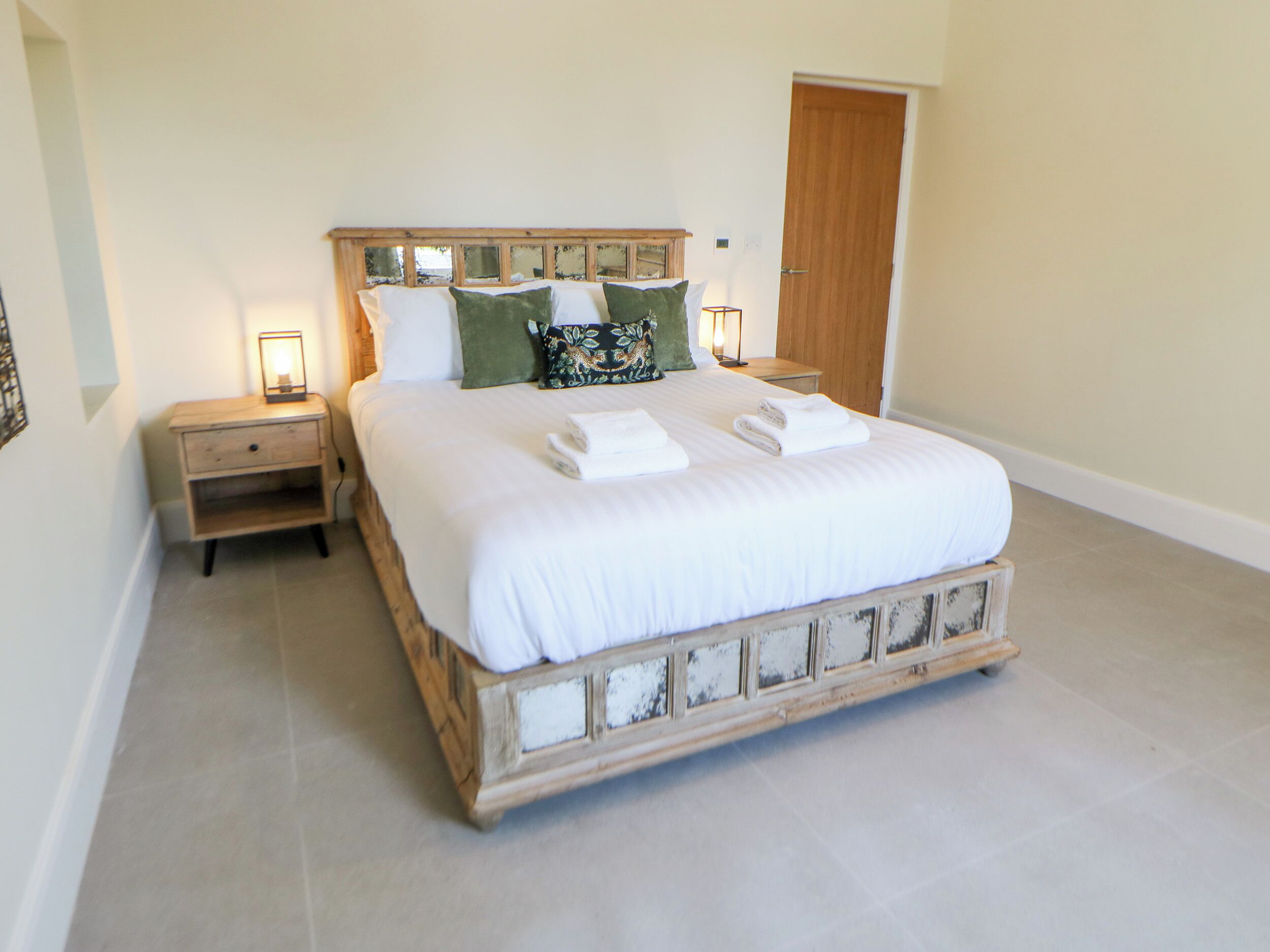 Una camera da letto con un letto grande, due comodini, una testiera in legno e una porta.