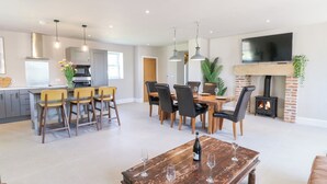 A modern kitchen with a dining area, a fireplace, and a TV mounted on the wall. - The Workshop (Northallerton)