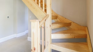 A wooden staircase with a handrail and a landing. - The Workshop (Northallerton)