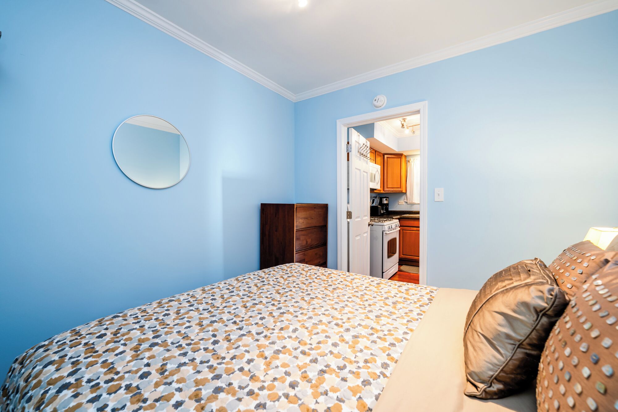 Une chambre à coucher avec un lit, des oreillers, une commode et un miroir.