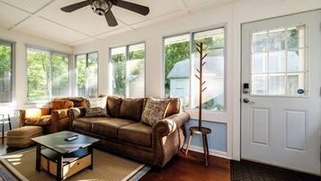 A cozy living room with a brown leather sofa, a wooden coffee table, and a ceiling fan.