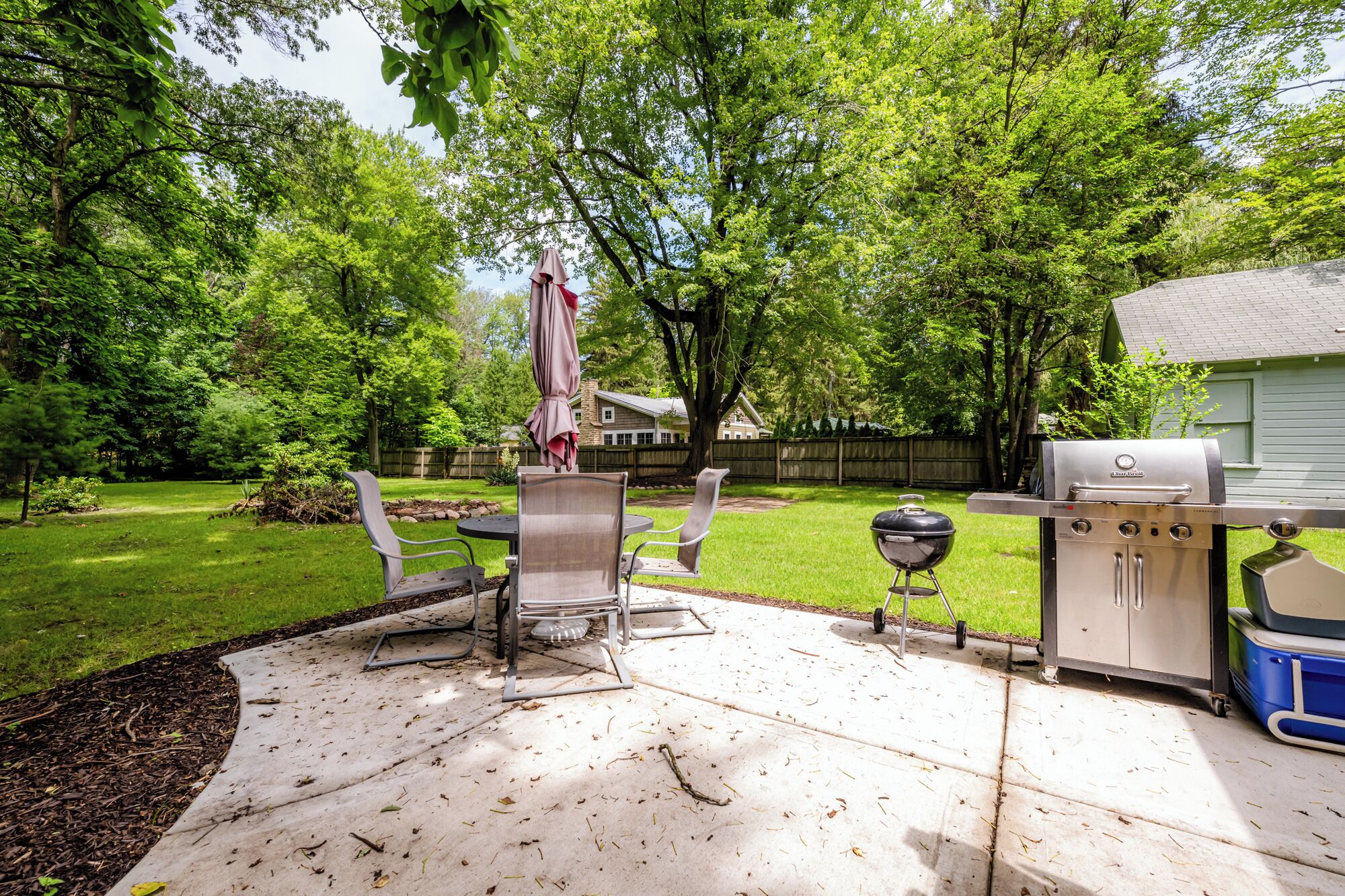A backyard with a patio area, a grill, and outdoor furniture.