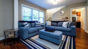 A modern living room with a grey sectional sofa, a small round table, and a striped rug. - 2027 OPEN! 3 Night Min~Union Pier Home Close To Beach and Downtown! (Union Pier)