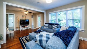 A modern living room with a grey sectional sofa, a flat-screen TV, and a ceiling fan. - 2027 OPEN! 3 Night Min~Union Pier Home Close To Beach and Downtown! (Union Pier)