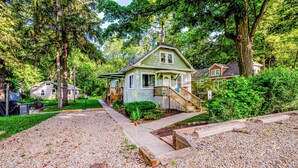 A single-story house with a front porch, surrounded by trees and a gravel driveway. - 2027 OPEN! 3 Night Min~Union Pier Home Close To Beach and Downtown! (Union Pier)