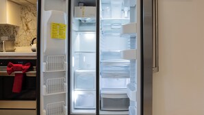 Une cuisine moderne avec un réfrigérateur encastré, un meuble en bois au-dessus et un tableau accroché au mur.